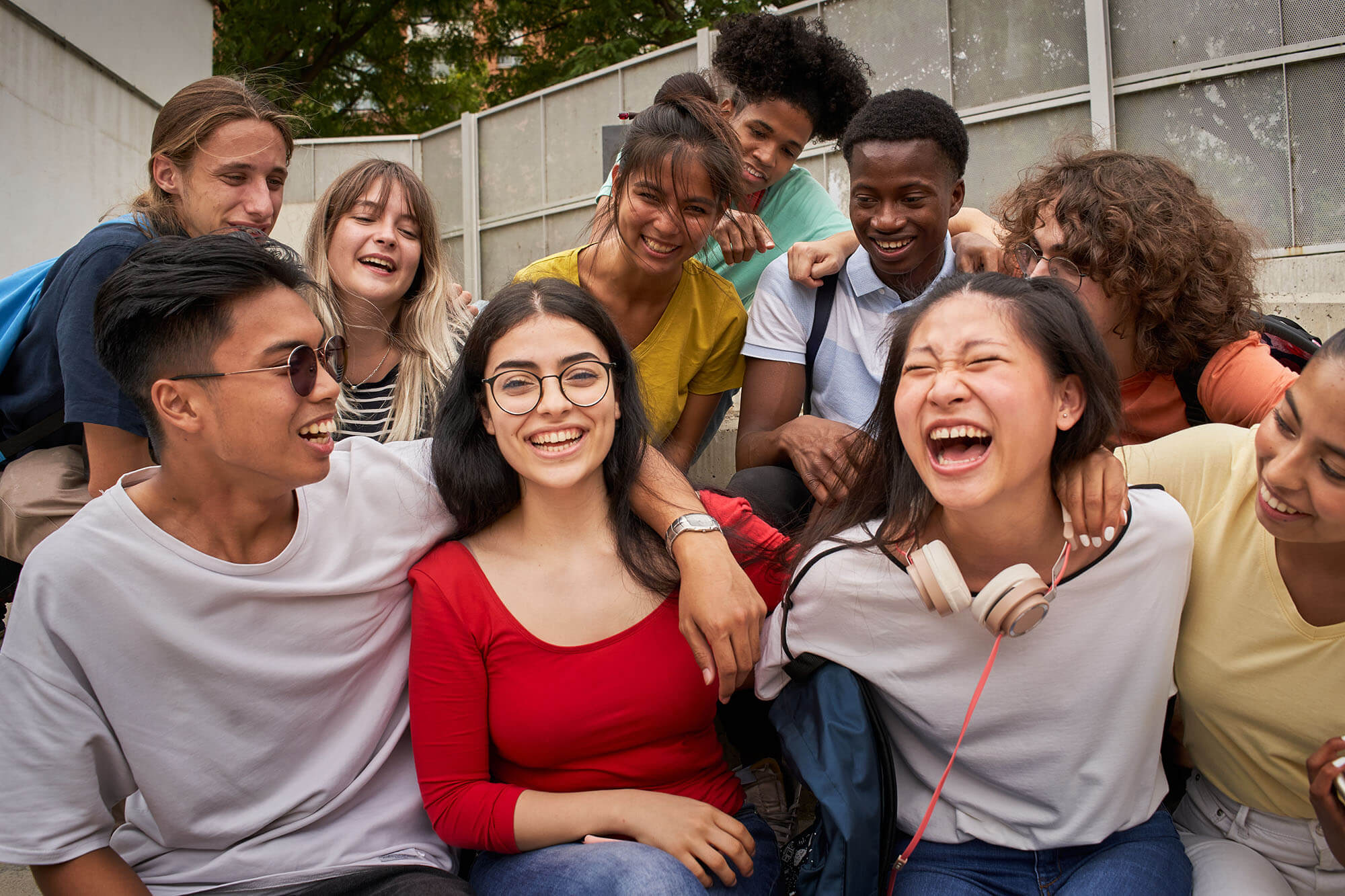 gear-up-applications-image-0526 A diverse group of multiethnic high school teenagers laughing and smiling closely together outdoors.