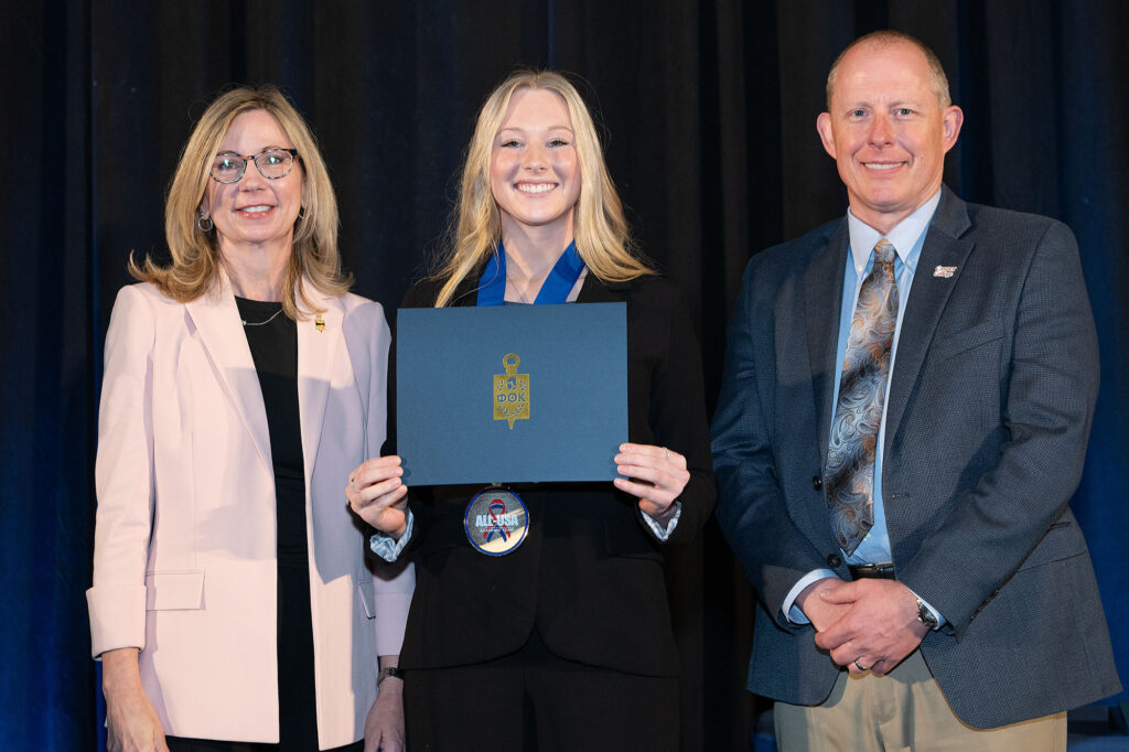 [Insert Name], Ahnya Ivie-Moody, and Dr. Brandon Kosine holding a Phi Theta Kappa certificate and wearing an All-USA Academic Team medal.