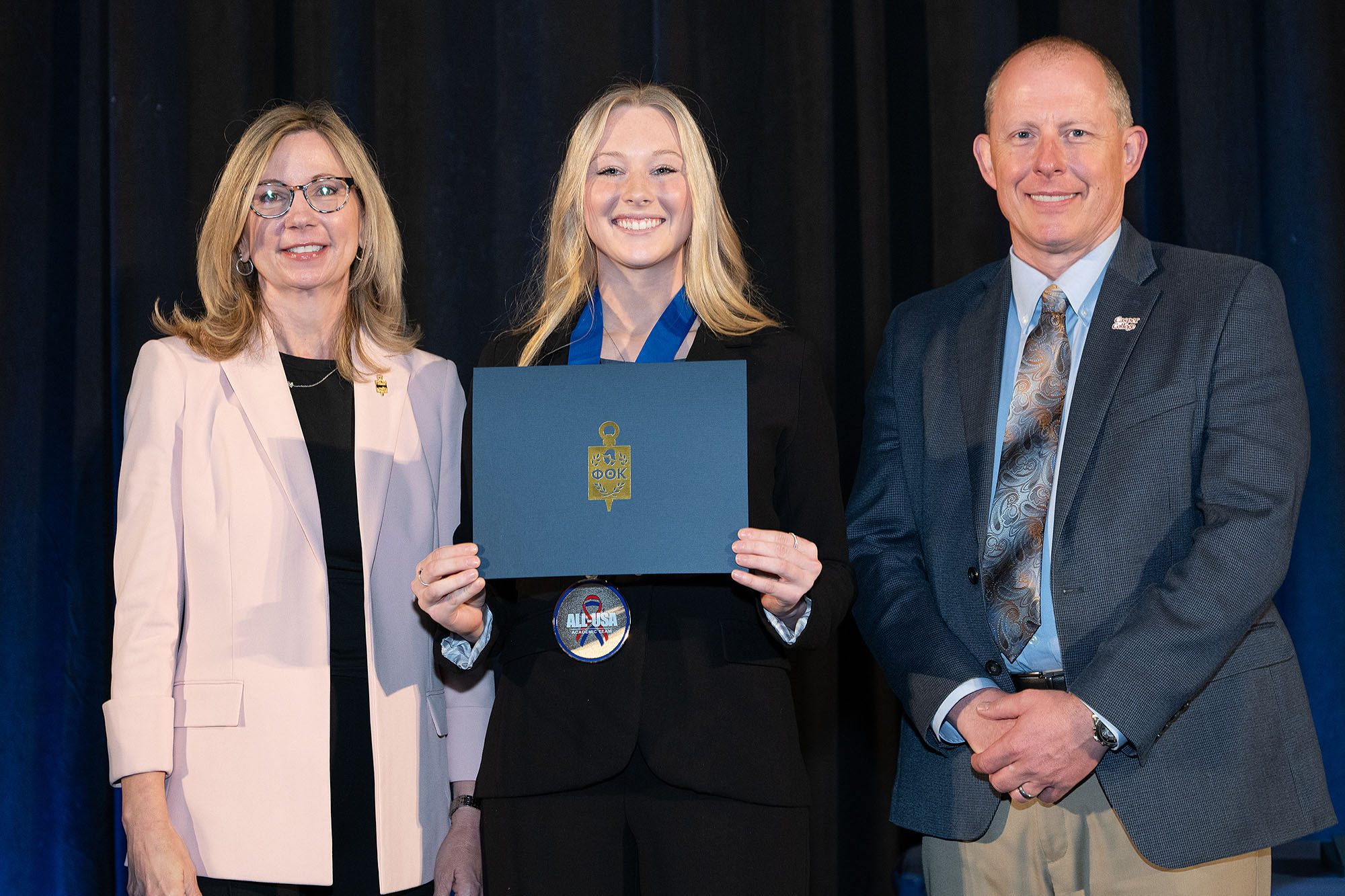 [Insert Name], Ahnya Ivie-Moody, and Dr. Brandon Kosine holding a Phi Theta Kappa certificate and wearing an All-USA Academic Team medal.