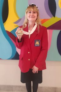 Fionna Kerkes holding up her official gold SkillsUSA Champion medal.