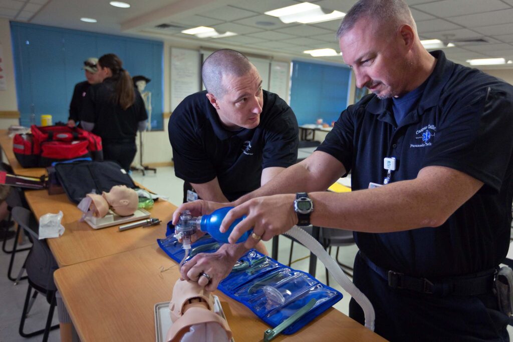Instructor demonstrates bag-valve-mask ventilation techniques during hands-on emergency airway management training.
