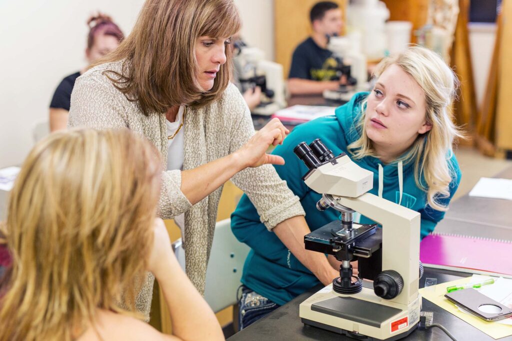 Instructor assists students with microscope techniques during a laboratory exercise.