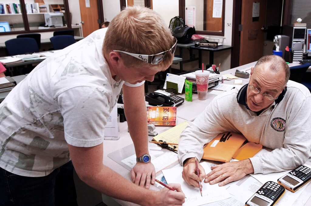 Student receives one-on-one assistance from an instructor while working through math problems.