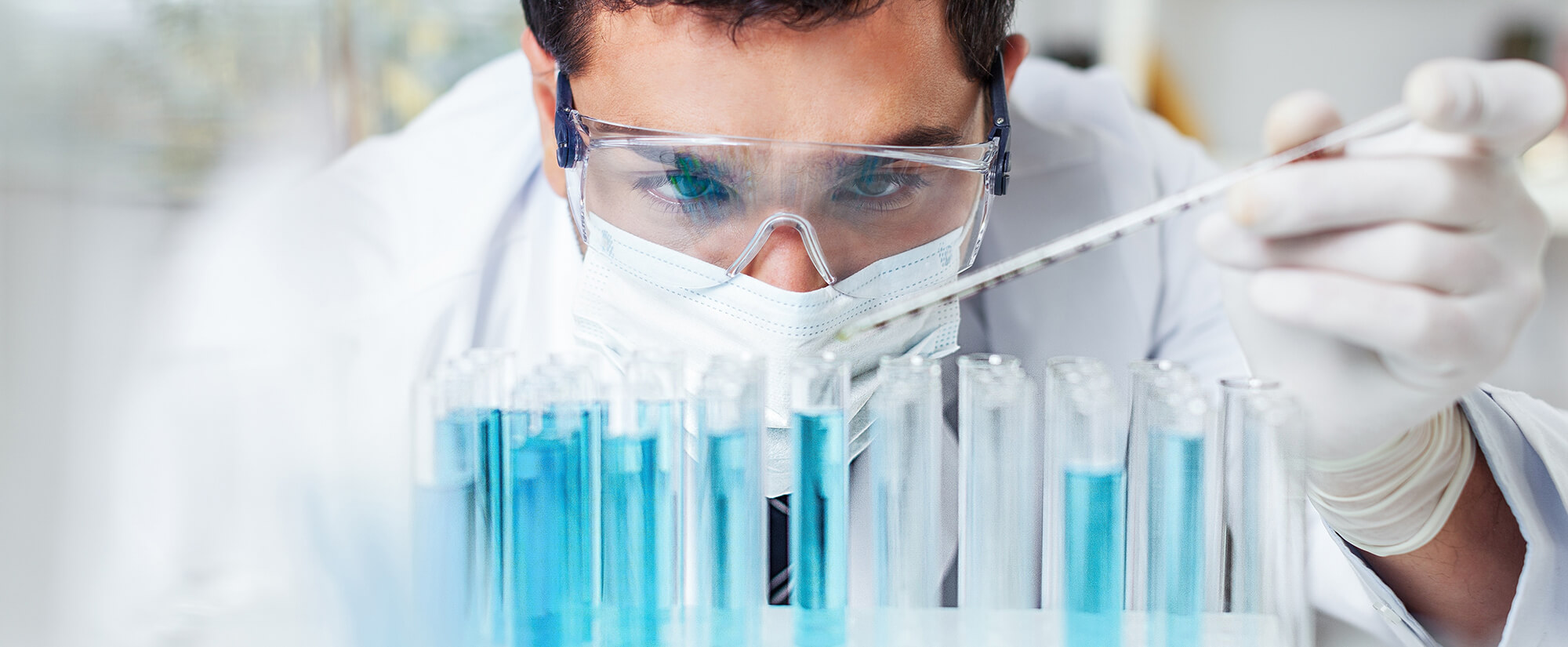 Photo of a medical technician filling vials with fluid.