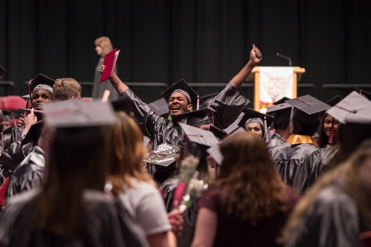 Photo of a student with arms up in celebration at a Casper College graduation ceremony